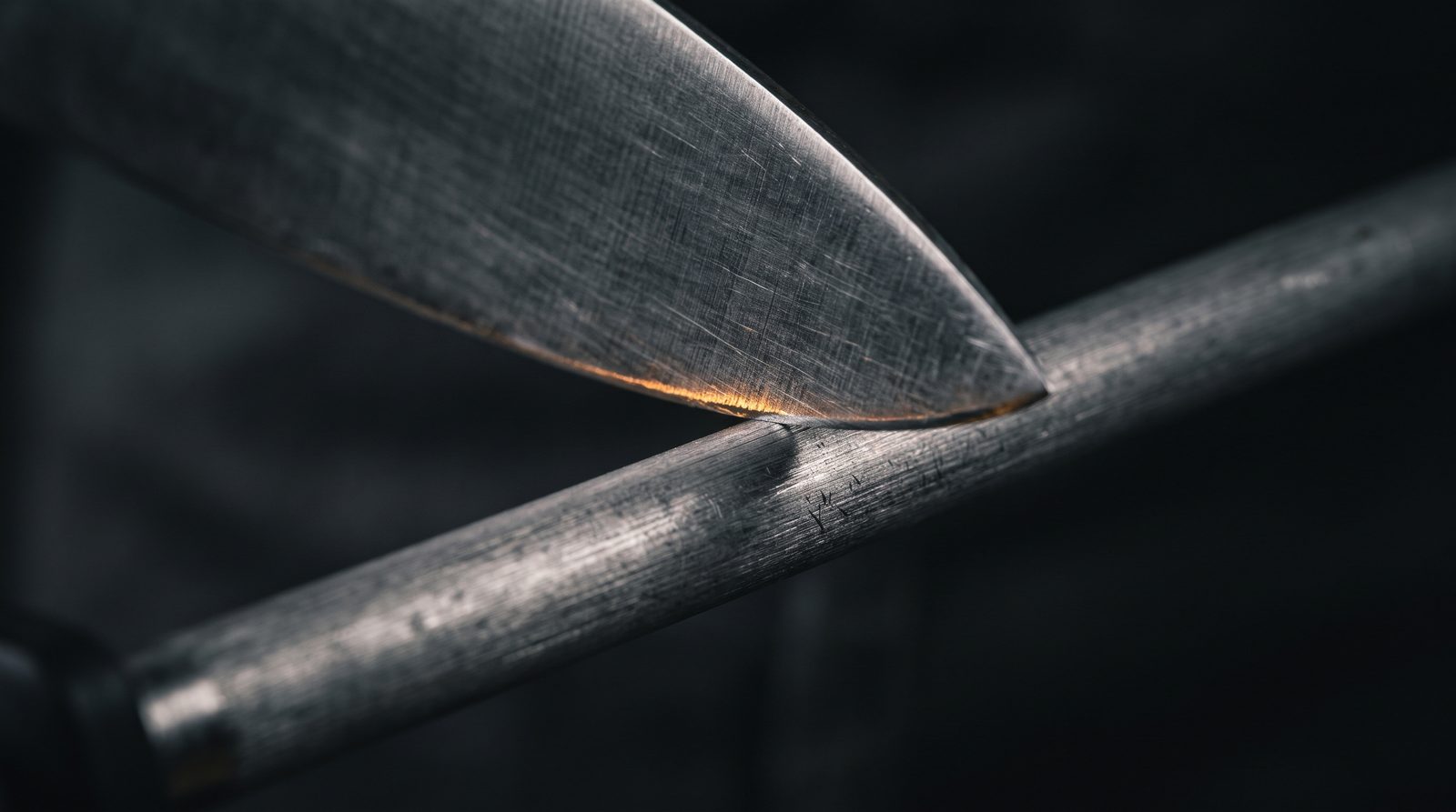 The edge of a chef's knife being drawn along a honing steel
