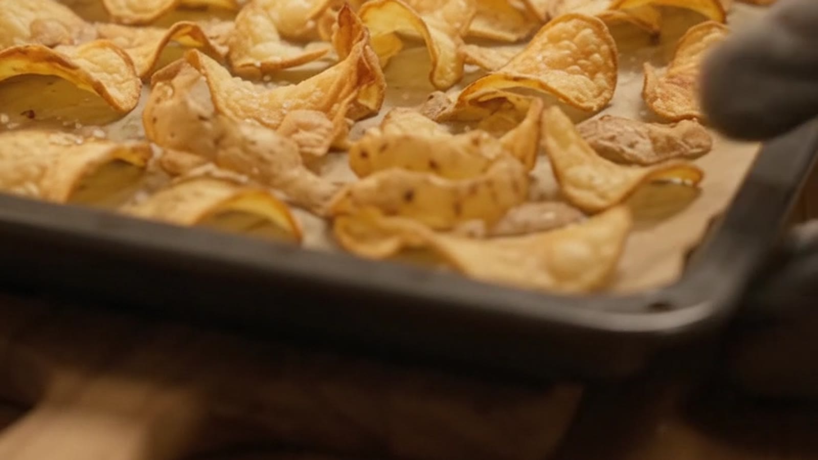 Golden curled potato peel crisps on a baking tray lined with baking paper